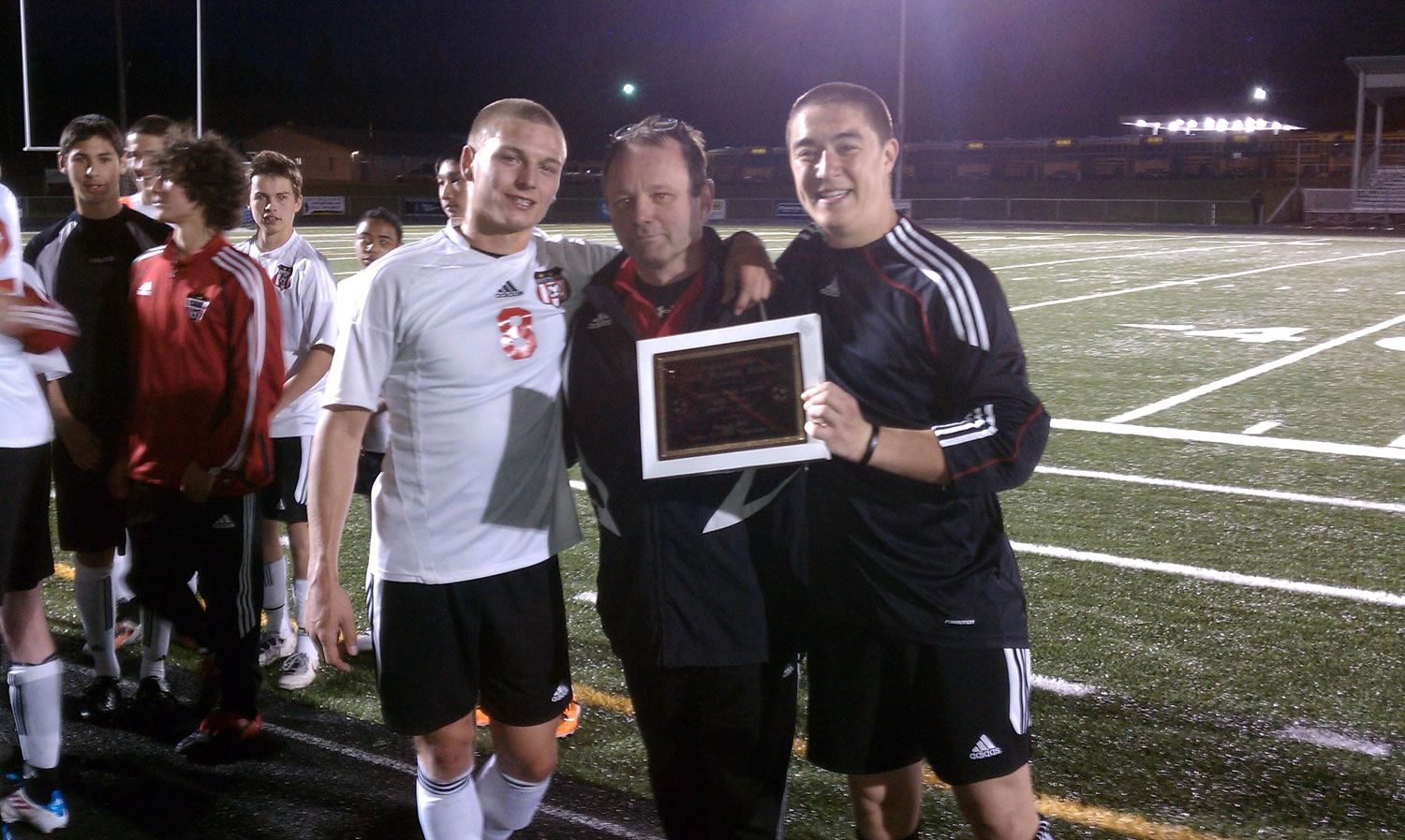 Camas High School soccer coach Roland Minder celebrates his 250th victory with seniors Drew White (left) and Zach Anderson (right).