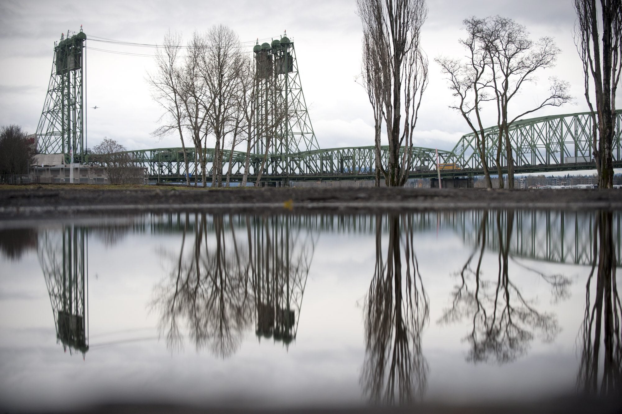 The waterfront and the Interstate 5 Bridge is seen reflected in a puddle left by December rain in Vancouver.
