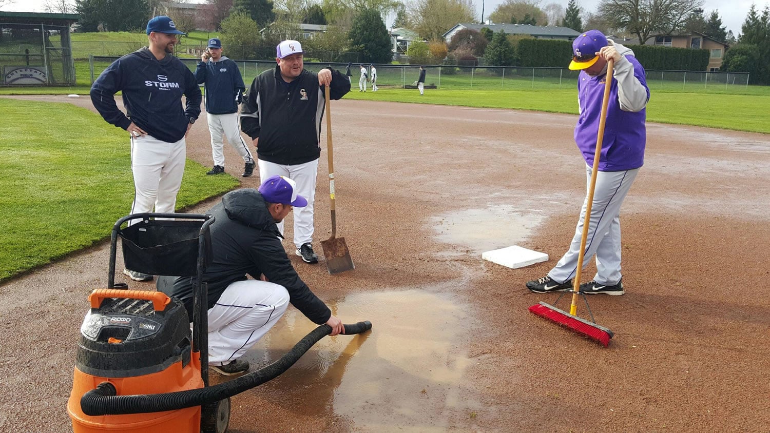 Coaches from the Skyview and Columbia River baseball teams try to get the Columbia River High School baseball field dry before a game last season. Teams have faced worst weather problems this year.