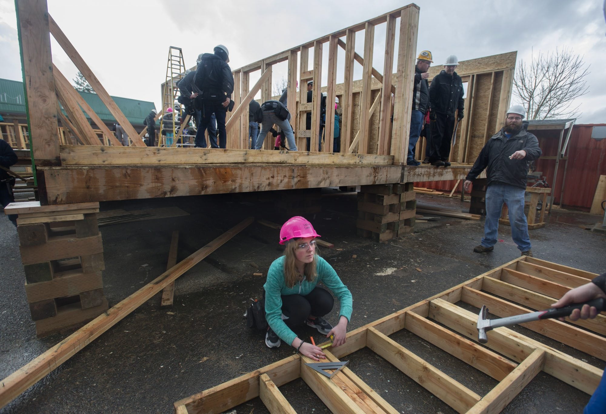 Evergreen High School sophomore Hailey Crater, 15, center, uses her math skills to measure a framed-out exterior wall on a Habitat for Humanity home students are building in their Geometry in Construction class.