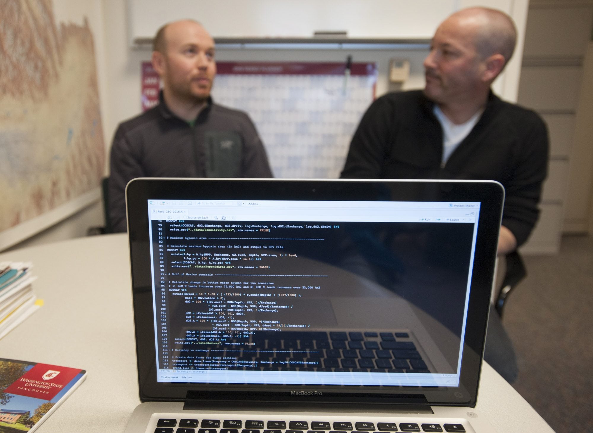 Daniel Reed and John Harrison, scientists at Washington State University Vancouver, discuss their work while a computer displays the code they developed to predict coastal dead zones around the world.
