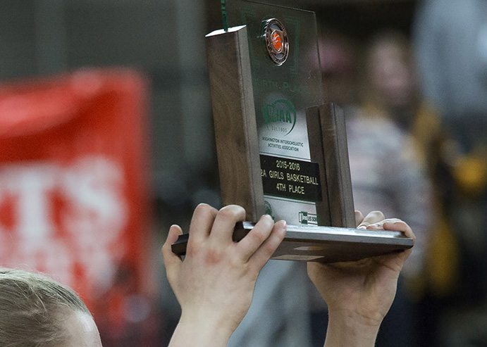 Washougal High School’s Raeann Allens hoists the fourth-place trophy as she and her teammates celebrate after beating Black Hills High School 50-28 in the class 2A girls state basketball tournament March 5, 2016 in the Yakima SunDome in Yakima, Wash.