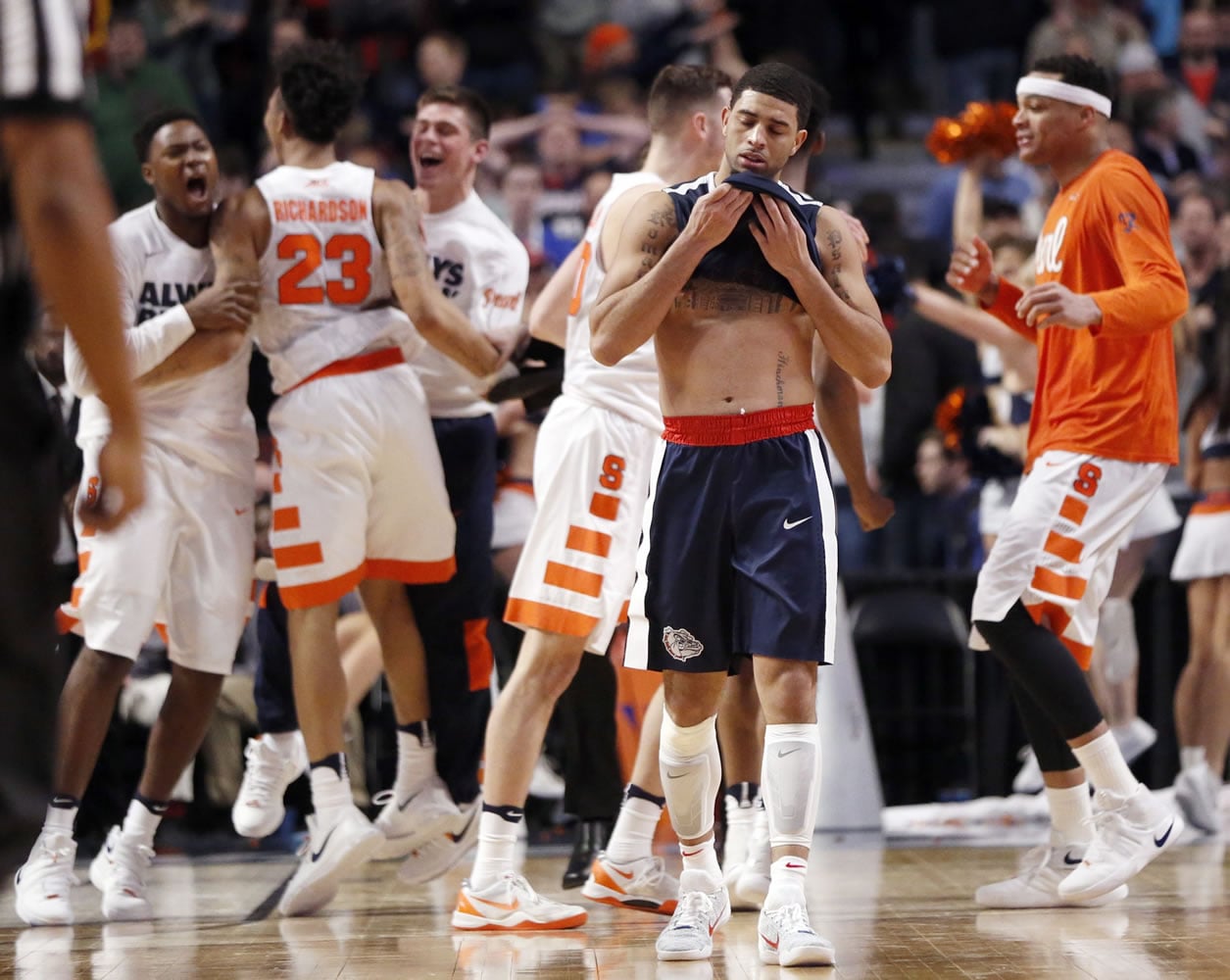 Gonzaga&#039;s Josh Perkins (13) walks off the court as Syracuse players celebrate after a college basketball game against Syracuse in the regional semifinals of the NCAA Tournament, Friday, March 25, 2016, in Chicago. Syracuse won 63-60.