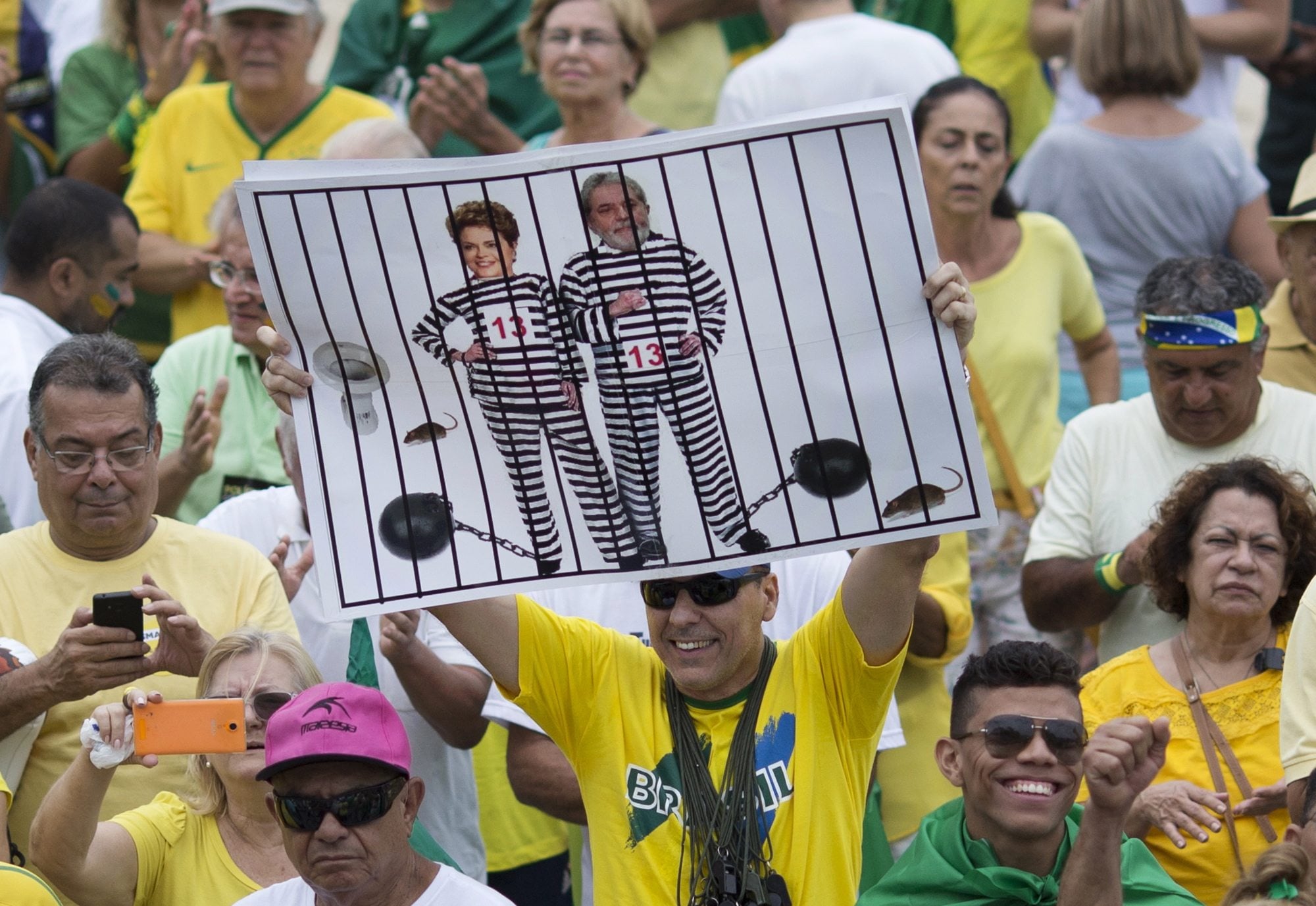 A demonstrator holds a poster with the photo of Brazilian president Dilma Rousseff and former President Luiz Inacio Lula da Silva in prison stripes during a protest on Copacabana beach in Rio de Janeiro, Brazil. It was the best of times in 2009 when Rio was awarded the games, championed by then-President Luiz Inacio Lula da Silva. He called it a &quot;sacred day&quot; and praised the &quot;strength of Brazil&#039;s economy,&quot; which shrank by 4 percent in 2015 with no improvement in sight.