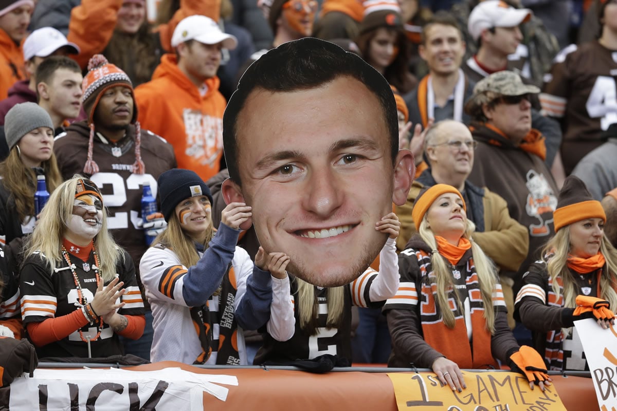 Fans hold a large cutout of Cleveland Browns quarterback Johnny Manziel during a Dec. 14, 2014, NFL football game against the Cincinnati Bengals, in Cleveland. The Browns have released troublesome quarterback Johnny Manziel. The team cut ties on Friday with the 2012 Heisman Trophy winner after two disappointing, drama-filled seasons. Manziel faces an uncertain future in the NFL and potential criminal charges in Texas following a domestic violence incident.