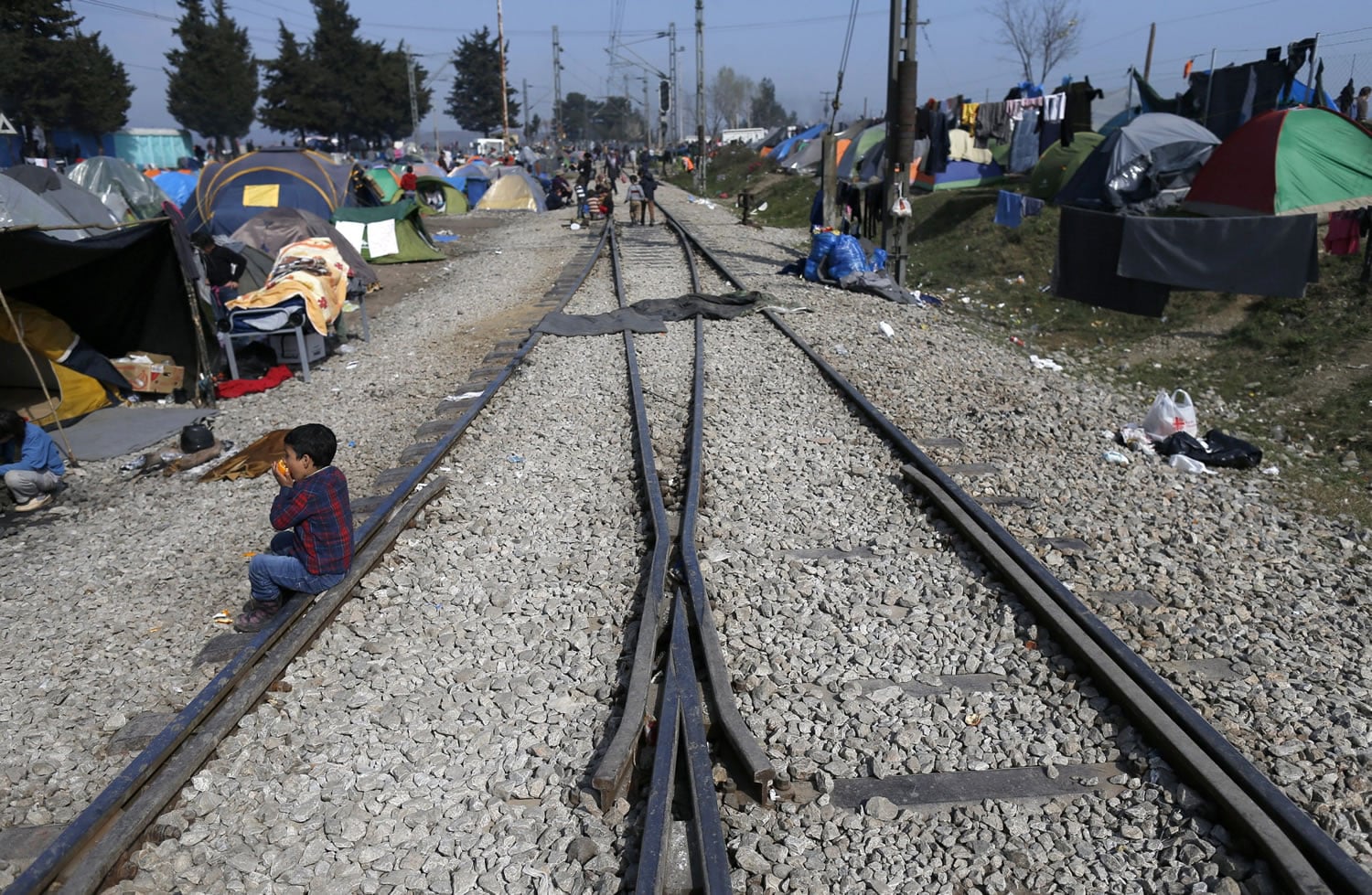 A migrant boy eats at a train station near a makeshift refugee camp Monday at the northern Greek border point of Idomeni, Greece. Hundreds of mostly Syrian asylum-seekers continued to arrive in Greece by sea.