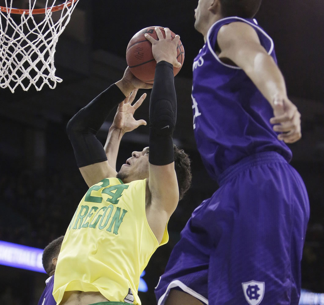 Oregon forward Dillon Brooks (24) shoots against of Holy Cross forward Eric Green, right, and forward Malachi Alexander (21) during the first half of a first-round men's college basketball game in the NCAA Tournament in Spokane, Wash., Friday, March 18, 2016.