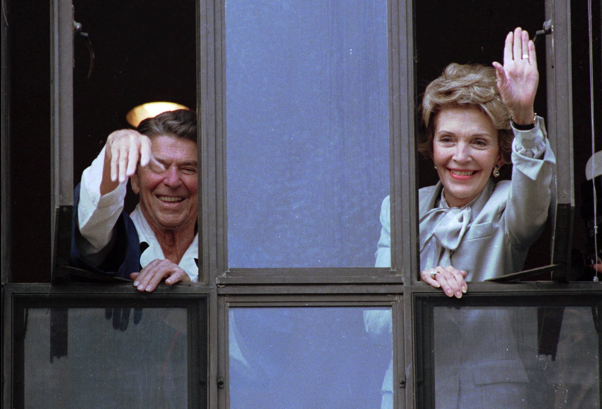 FILE - In this July 18, 1985, file photo, President Ronald Reagan and his wife, Nancy, wave from windows of his hospital room at the Navy Medical Center in Bethesda, Md., on July 18, 1985.
