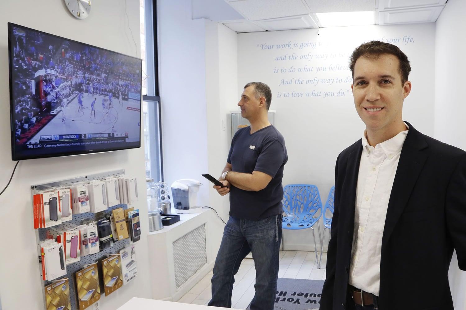 Joe Silverman, right, poses in the lobby of his New York computer repair shop while employee Alex Lokshin watches the company&#039;s big-screen TV.