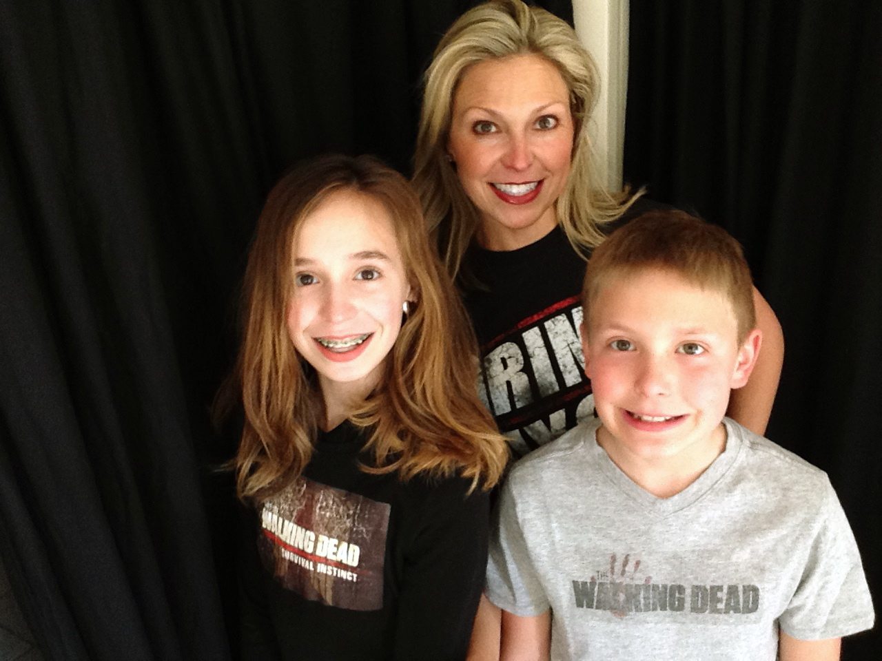 This March 29, 2016 photo released by Ericka Calcagno, center, shows her with her daughter Gina Binder, 12, left, and son Jean-Luc Binder, 9, wearing T-shirts from, &quot;The Walking Dead,&quot; at their home in Farmington Hills, Mich. Calcagno says her husband first introduced her to the series and her kids were intrigued by their conversations about it. And now they all watch the popular zombie show as a family.