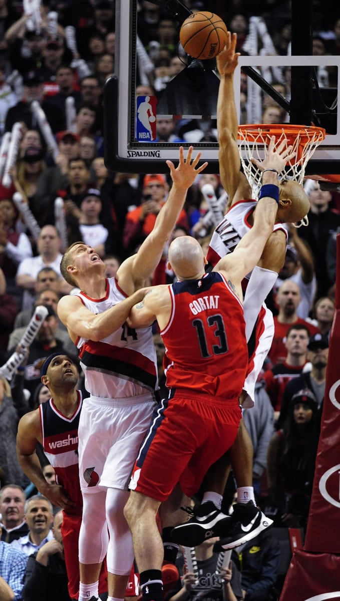 Portland Trail Blazers guard Gerald Henderson (9) blocks the shot of Washington Wizards center Marcin Gortat (13) as Trail Blazers center Mason Plumlee (24) defends during overtime of an NBA basketball game in Portland, Ore., Tuesday, March 8, 2016. The Blazers won 116-109.
