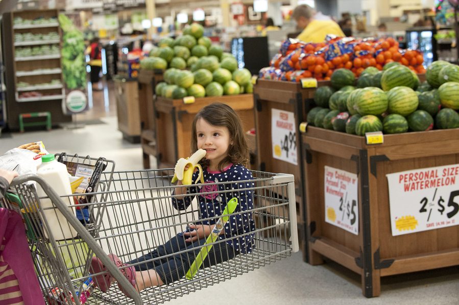 Maisy Fels, 3, of Vancouver snacks on a free banana while shopping with her grandmother Katy Miller on Tuesday afternoon at the Fisher&#039;s Landing Fred Meyer. The grocery chain recently launched its Fruit for Kids program that offers children a free piece of fruit while shopping.