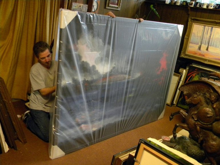 Art transporter Bruce Dailey wraps plastic around Gordon Sage&#039;s painting of the attack on Pearl Harbor before loading it on a truck Thursday.