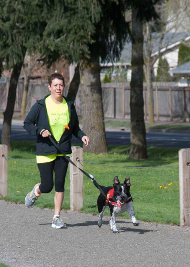 Jeanne Stevenson jogs with a dog as she trains for the upcoming 5K Walk/Run for the animals hosted by the Humane Society for Southwest Washington.