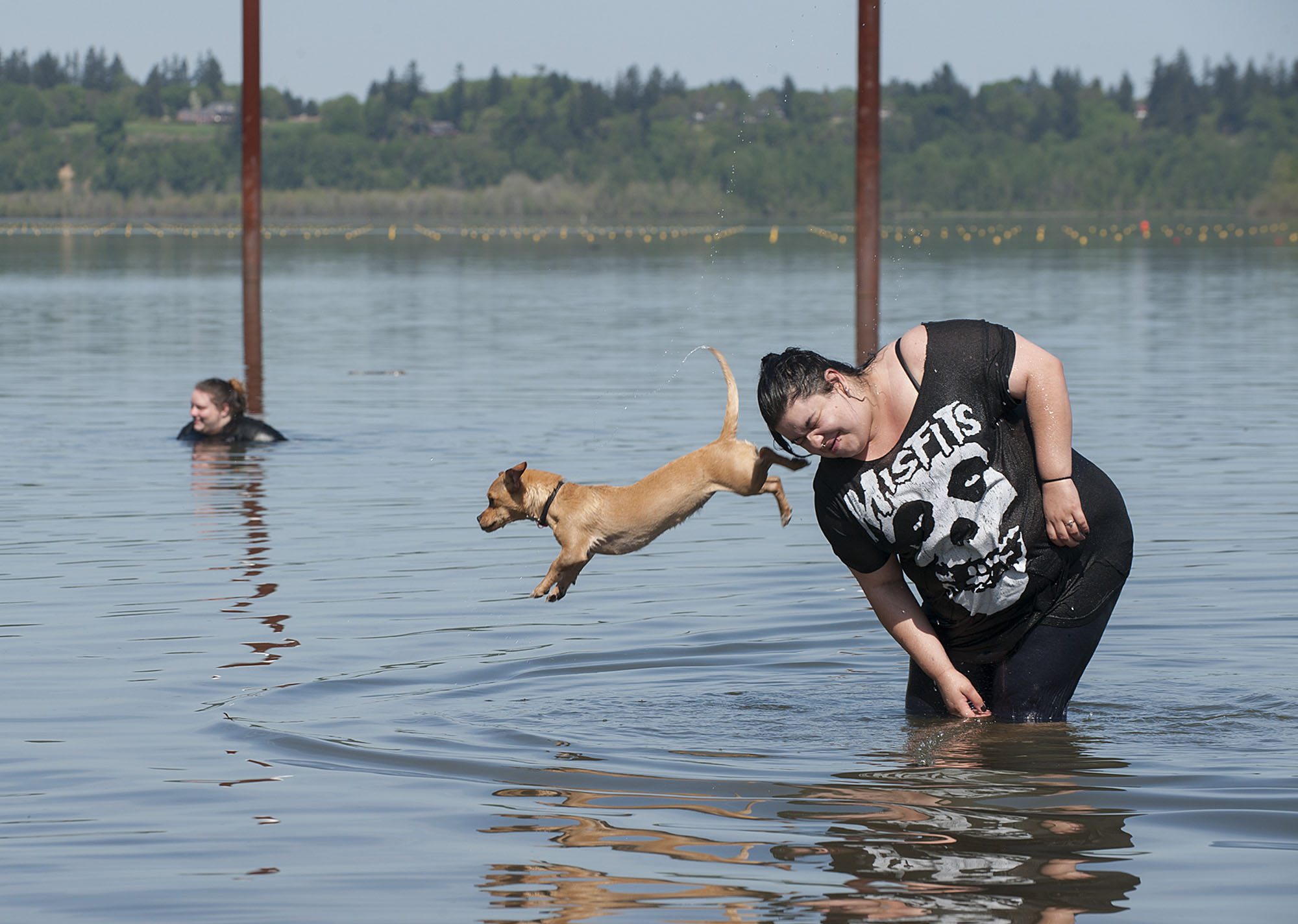Sara Ortiz of Yakima Valley escapes the unusually high temperatures by cooling off in the waters of Vancouver Lake as her dog, Stash, 9 months, leaps into the fun Monday afternoon, April 18, 2016.