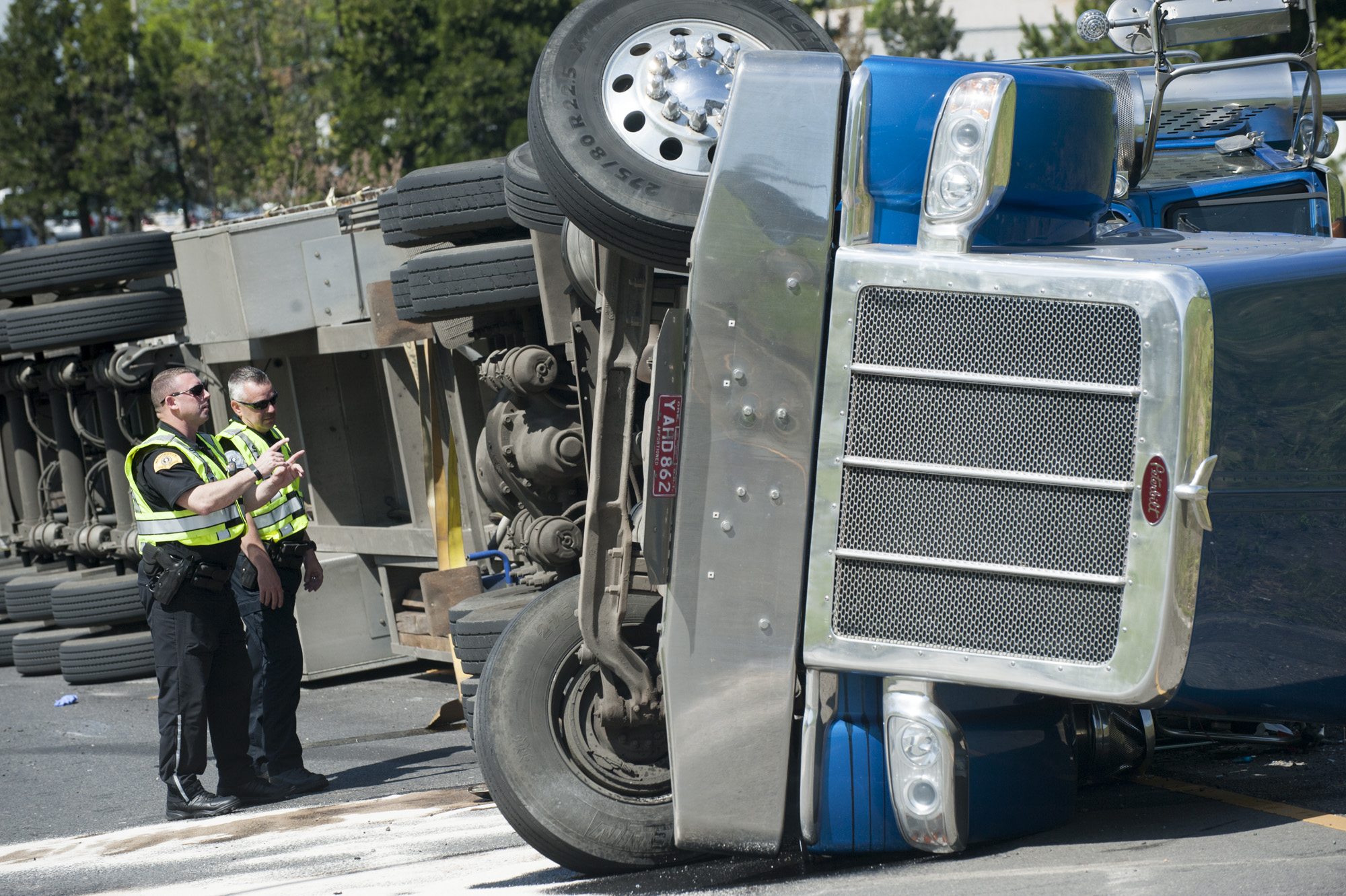 WSP Troopers Rob Gardiner, left, and Corey Turner survey the scene where a tractor-trailer overturned on the northbound I-5 exit to Highway 14 in Vancouver on Monday.