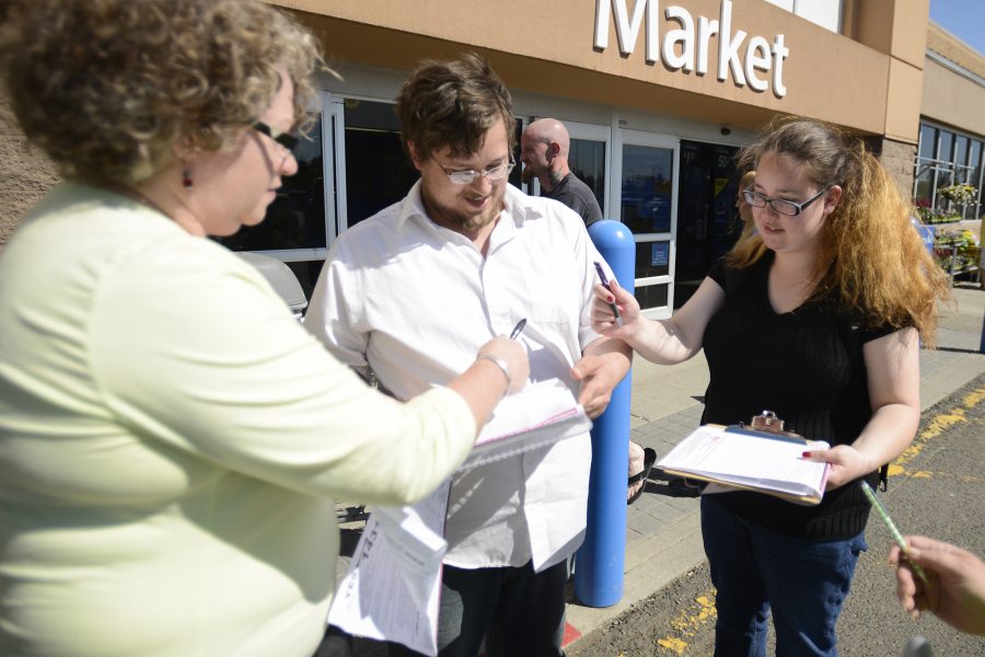 Alixandra Hunsucker, left, helps Chris Remor and April Chase, right, sign a petition that would put Initiative 1431, the so-called grandparent visitation initiative, on the November ballot. The initiative would allow a nonparent relative to petition the court for visitation with a child.