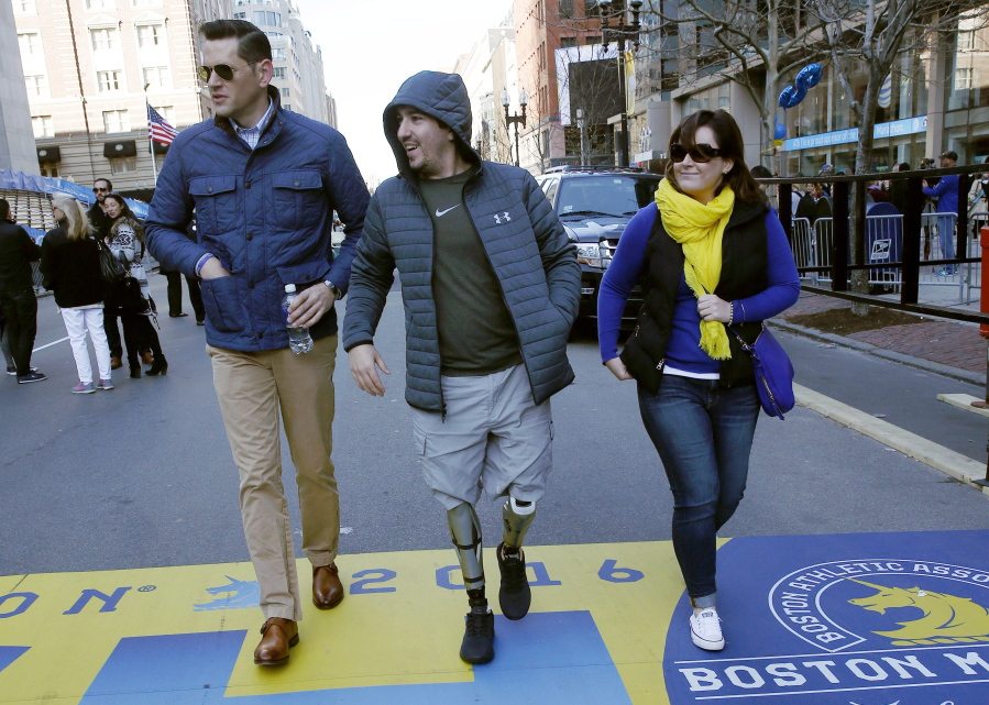 Boston Marathon bombing survivor Jeff Bauman, center, walks over the marathon finish line Friday on the third anniversary of the bombings in Boston. One of the bombers, Dzhokhar Tsarnaev, was sentenced to death in June. His brother, Tamerlan, died in a gunfight with police in the days after the attack.