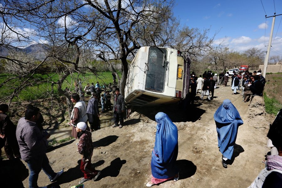Afghan women walk past a damaged bus Monday after a roadside bomb explosion on the outskirts of Kabul, Afghanistan. The Afghan Taliban have announced the start of their warm-weather fighting season, an annual declaration that marks the launch of a summer of violence.