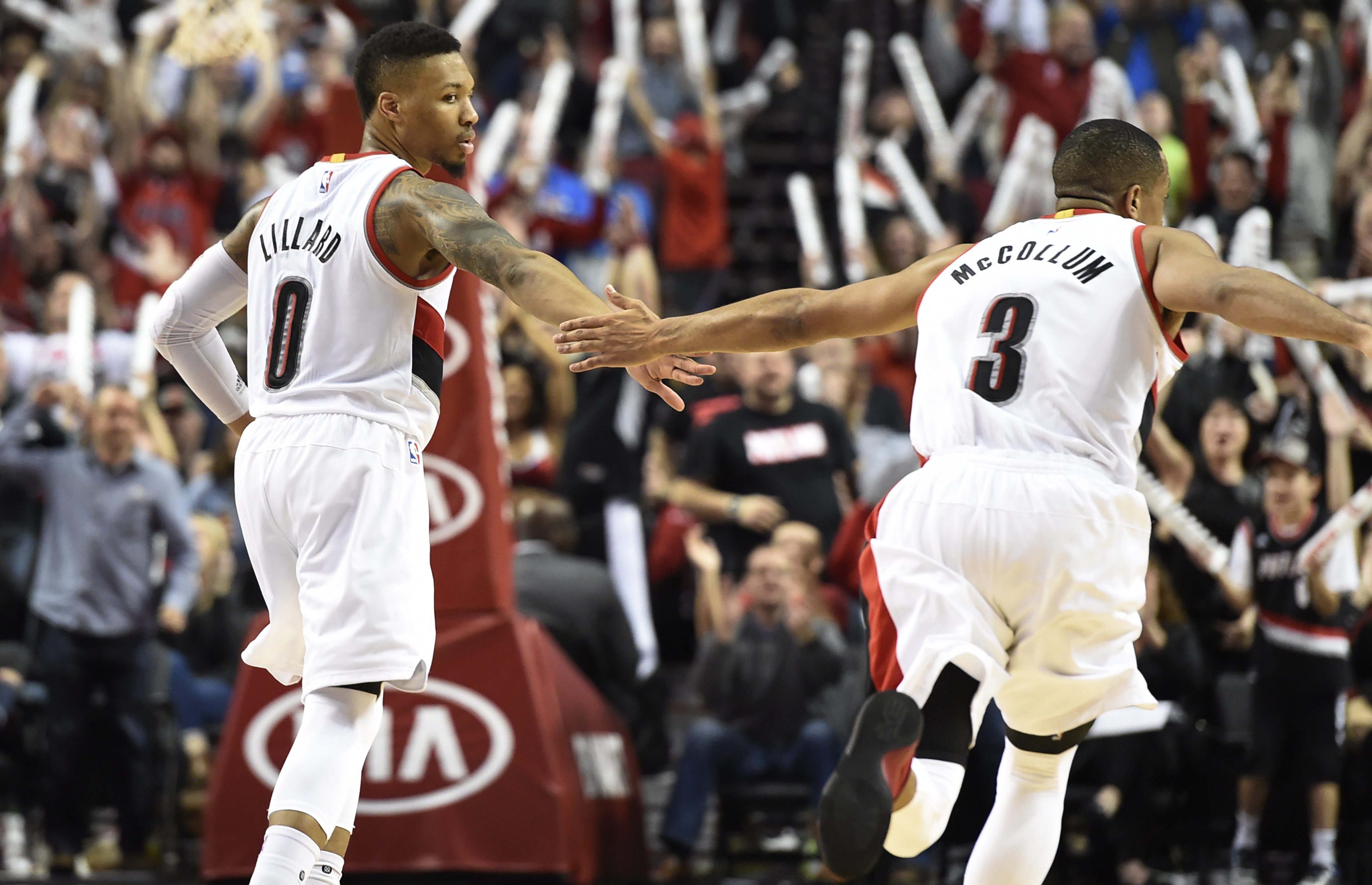 Blazers guard Damian Lillard (0) celebrates with teammate C.J. McCollum (3) after hitting a shot late in the fourth quarter against the Philadelphia 76ers.