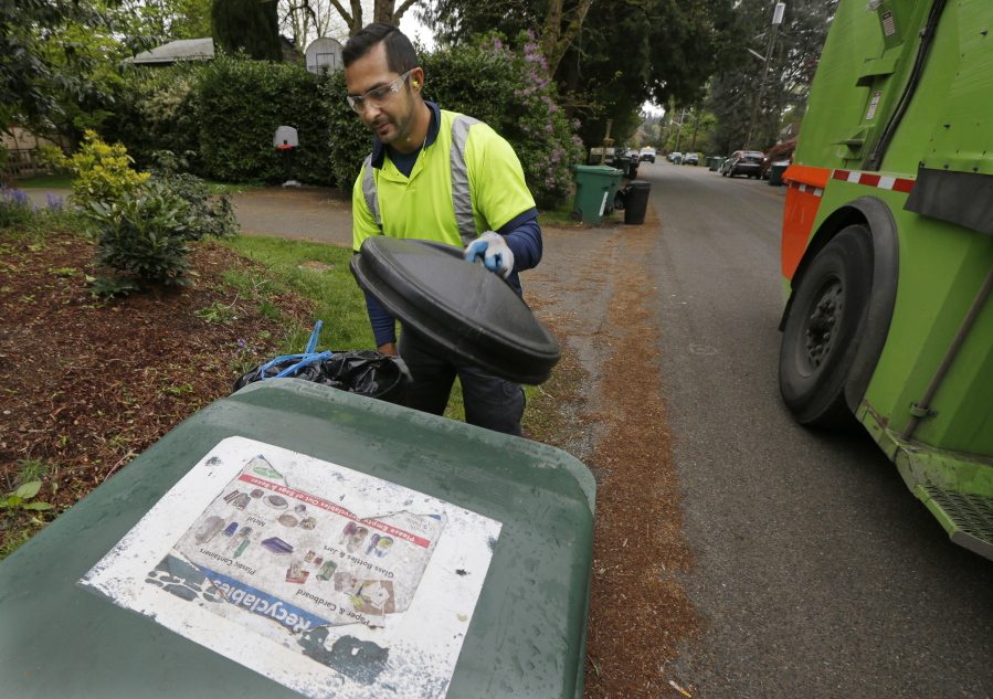 David Morales, a garbage driver with Recology, picks up a garbage container Friday for Seattle Public Utilities. A judge heard a challenge Friday to a new Seattle law allowing garbage collectors to check people&#039;s trash to see if they are disposing of recycling items and food waste incorrectly. (Ted S.