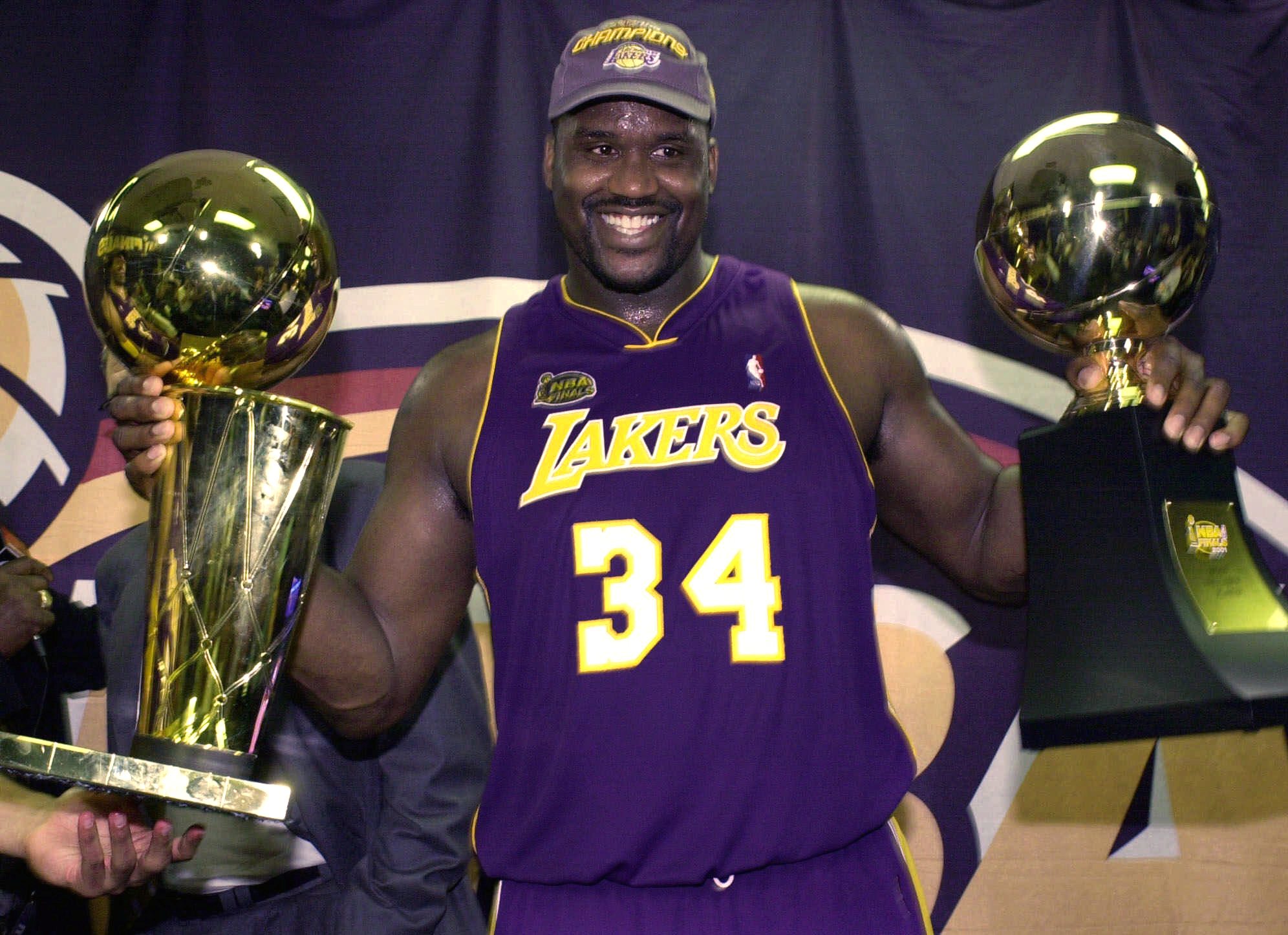 Los Angeles Lakers' Shaquille O'Neal holds up the MVP trophy, right, and the championship trophy  in 2001. (AP Photo/Mark J.