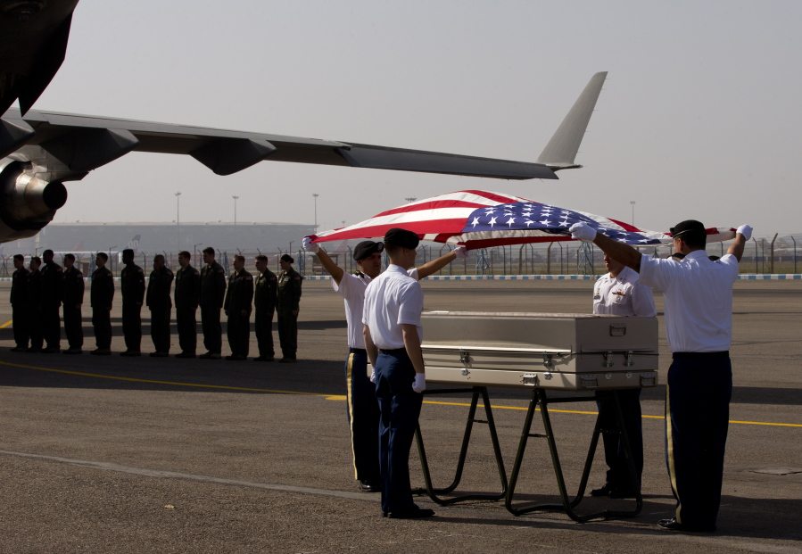 Members of the U.S. military on Wednesday drape a flag over what is believed to be remains of crew members from a World War II-era plane crash at a ceremony at the Palam airport in New Delhi, India. The B-24 bomber went missing in 1944 while on a supply run from India to China.