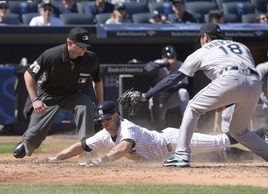 New York Yankees&#039; Brett Gardner scores on a wild pitch as Seattle Mariners pitcher Hisashi Iwakuma, right, takes the throw and home plate umpire Mike Muchlinski, left, looks on during the fifth inning of a baseball game, Sunday, April 17, 2016, at Yankee Stadium in New York.