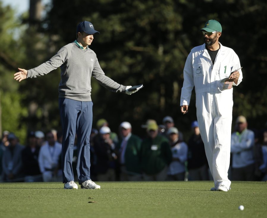 Jordan Spieth discusses his approach shot on the 15th hole with his caddie Michael Greller during the third round of the Masters golf tournament Saturday, April 9, 2016, in Augusta, Ga.