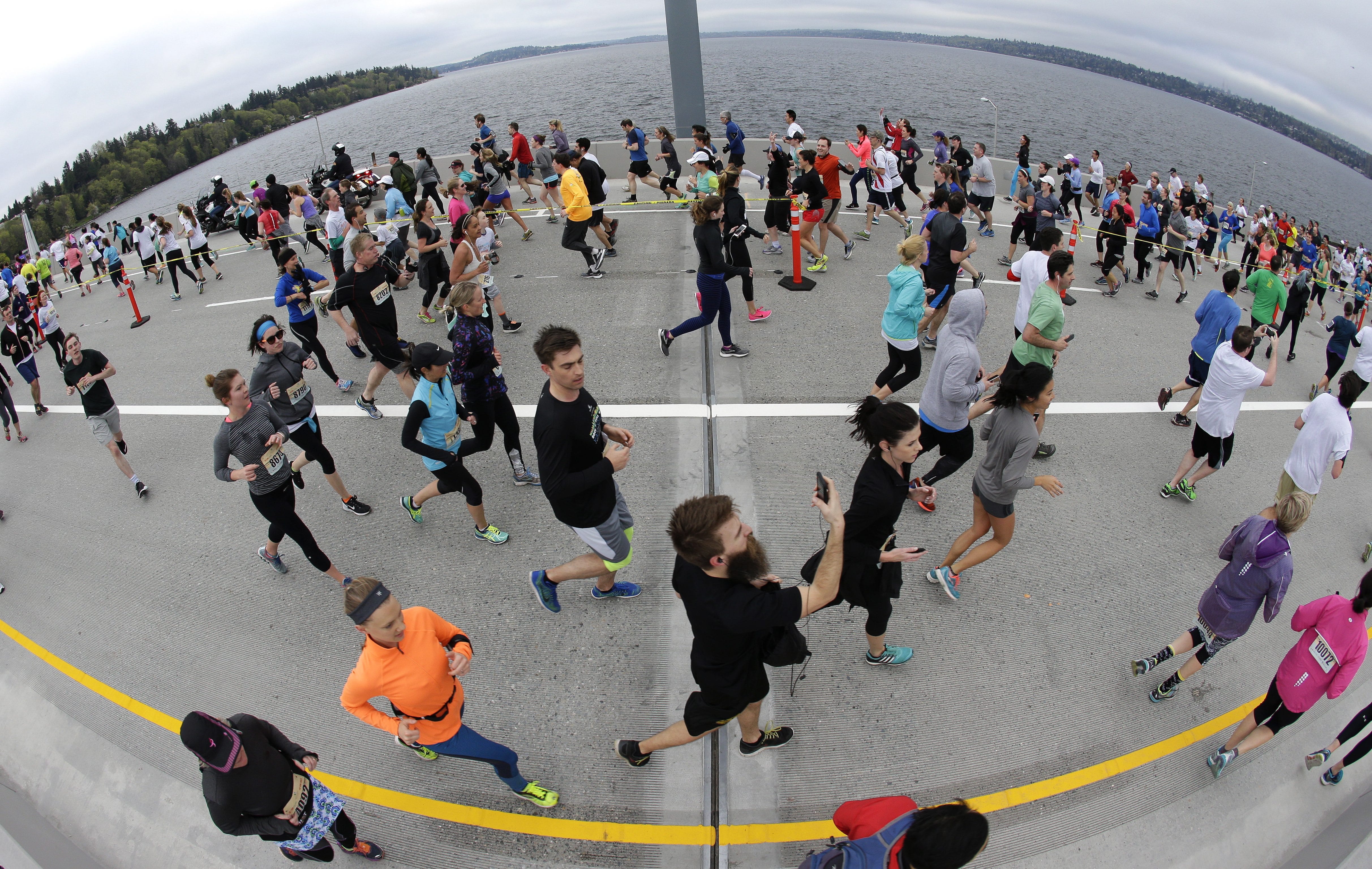 In this photo made with a  fish-eye lens, runners fill the eastbound lanes of the new State Route 520 floating bridge across Lake Washington, Saturday, April 2, 2016, during a 10K run to kick off weekend ceremonies for the grand opening of the span, which connects the cities of Seattle and Bellevue, Wash. The structure will open to vehicular traffic later in the month. (AP Photo/Ted S.