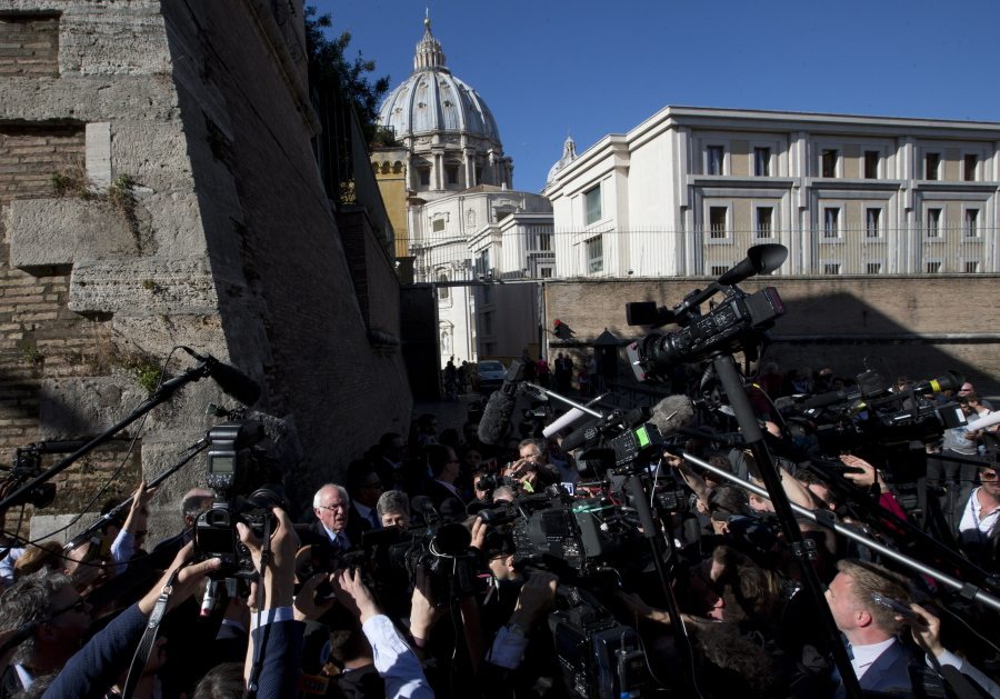 With the dome of St. Peter&#039;s Basilica in the background, Sen. Bernie Sanders is surrounded by reporters Friday at the Vatican, where he spoke at a conference.