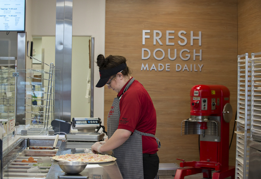 Tayler Smith creates a pizza March 9 at Papa Murphy&#039;s on East Mill Plain Boulevard. The company announced a profit for the first quarter of 2016 on Wednesday, though it was lower than the first quarter of 2015.