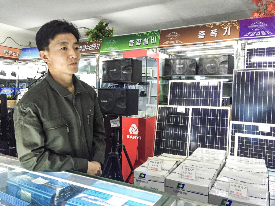 A clerk at the Potanggang Information Technology Center stands in front of a display of solar panels for sale in Pyongyang, North Korea.