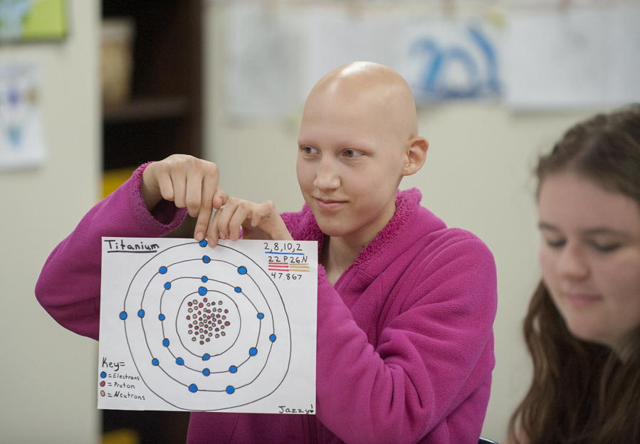 Seventh-grader Jasmine Erickson, 13, displays a diagram of titanium while working with fellow students including eighth-grader Mara Reese, also 13, right, at Lewis River Academy in Woodland.