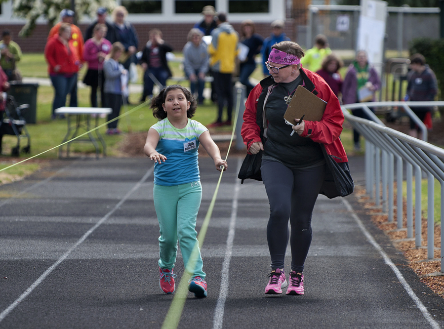 Millie Ortiz, 11, of Centralia, left, gets a little encouragement from J.J. Isaacson of Washington State School for the Blind during the 50-meter dash Thursday at the school.