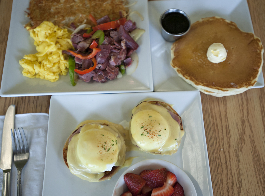 Eggs Benedict with fresh fruit, clockwise from bottom, are served with scrambled eggs, corned beef hash and pancakes on May 16 at Nayhely&#039;s Place in Hazel Dell.