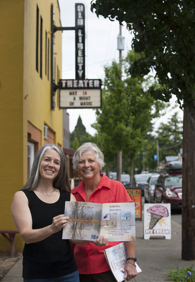 Ridgefield artists Maureen O’Reilly, left, and Patricia Thompson display a copy of O’Reilly’s new alphabet book featuring artwork from Ridgefield residents depicting sights around the city, including Old Liberty Theater, visible behind them.