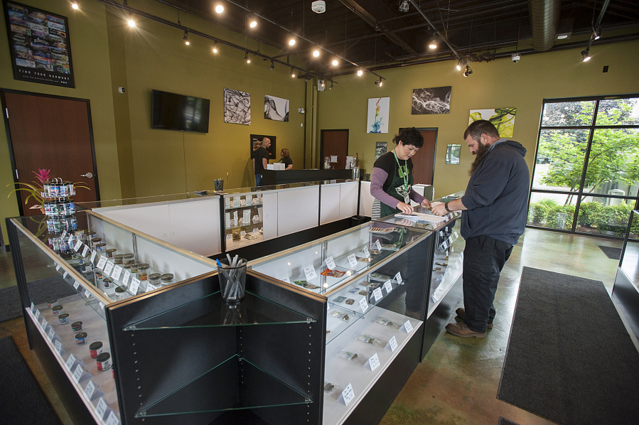 Budtender Alyssa Eng helps customer Mike Newhouse on May 20 at Main Street Marijuana&#039;s new location in east Vancouver. The shop joins a location in Uptown Village and in Longview as the store tries to create a &quot;regional presence,&quot; said owner Adam Hamide.