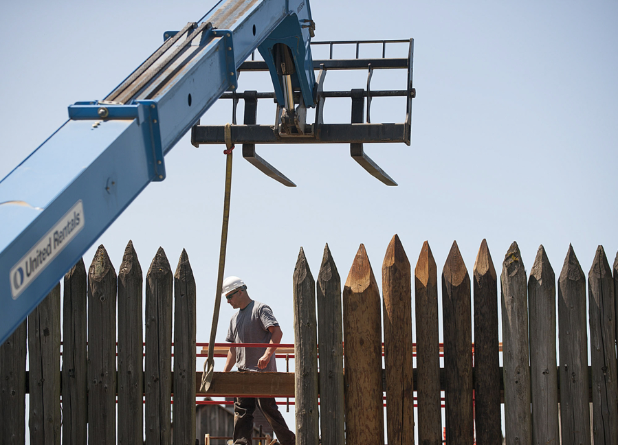 Matt Gembala helps get a replacement timber called a waler in place as Ausland Group workers renovate a section of the log palisade at the Fort Vancouver National Historic Site.