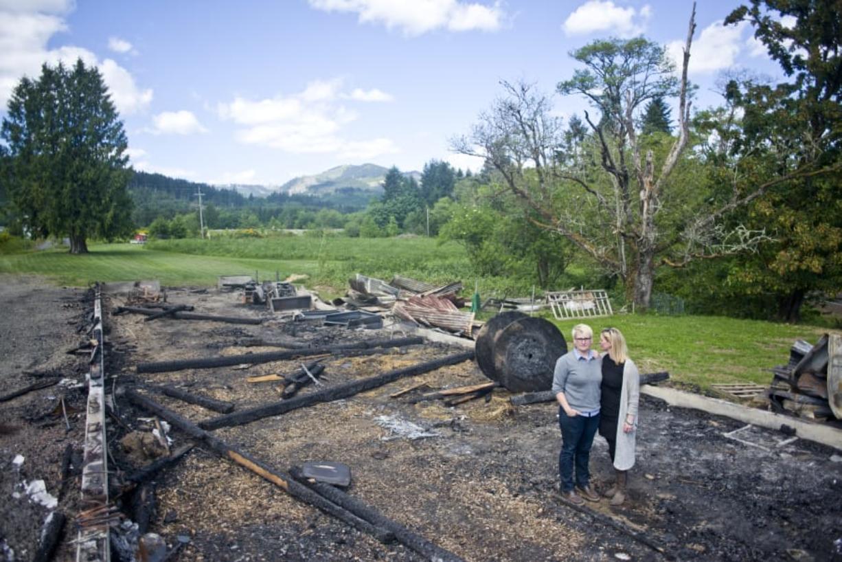 Jenny Stanton-Johnson, left, and her wife, Muriel Stanton-Johnson, stand where pig pens were in their storage barn and animal pavilion at Adeline Farms in Woodland. An April 27 fire that killed 11 animals destroyed it and hundreds of thousands of dollars of equipment.