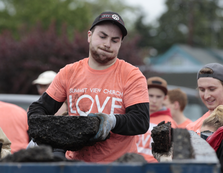 Volunteer Loren Egbert hauls away asphalt chunks removed Sunday from the parking lot of Everyday Deals in Vancouver&#039;s Rose Village neighborhood. Many volunteers from Summit View Church wore their “LOVE Vancouver” T-shirts, the name of a community service program at the church.