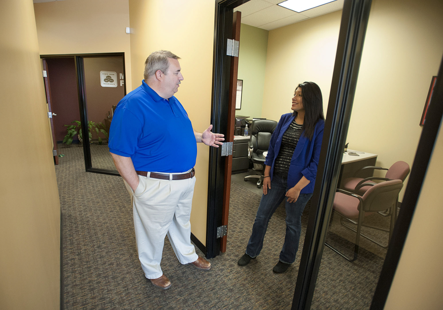 State Farm agent Michael Harris, left, talks with office representative Eliza Fausto at his office in Salmon Creek.