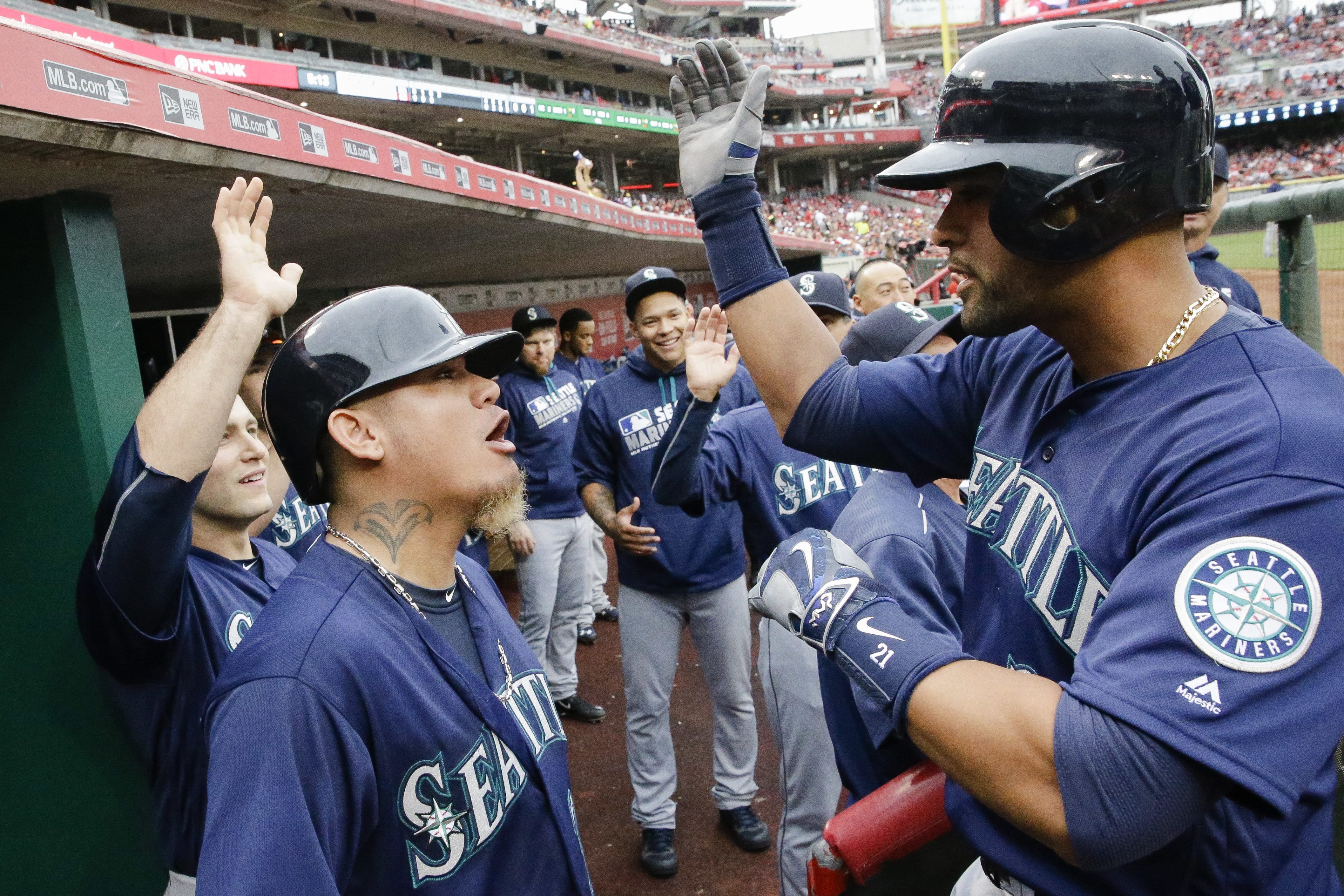 Seattle Mariners' Franklin Gutierrez, right, celebrates with Felix Hernandez, second from left, and teammates in the dugout after hitting a three-run home run off Cincinnati Reds starting pitcher John Lamb in the fourth inning of a baseball game, Saturday, May 21, 2016, in Cincinnati.