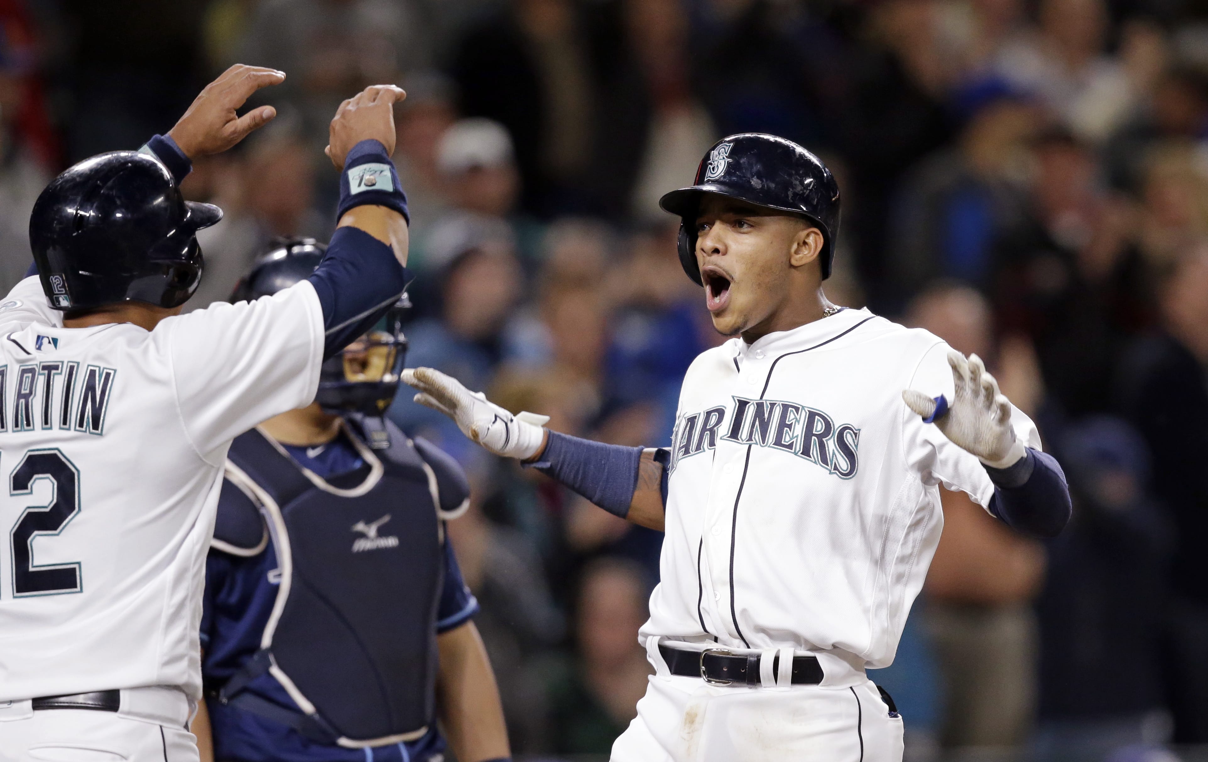 Seattle Mariners' Ketel Marte, right, is greeted by Leonys Martin as Marte crosses home on his three-run home run and Tampa Bay Rays catcher Hank Conger looks on in the sixth inning of a baseball game Monday, May 9, 2016, in Seattle.