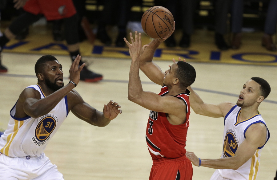 Portland Trail Blazers&#039; C.J. McCollum, center, shoots between Golden State Warriors&#039; Festus Ezeli, left, and Stephen Curry during the second half in Game 5 of a second-round NBA basketball playoff series, Wednesday, May 11, 2016, in Oakland, Calif.
