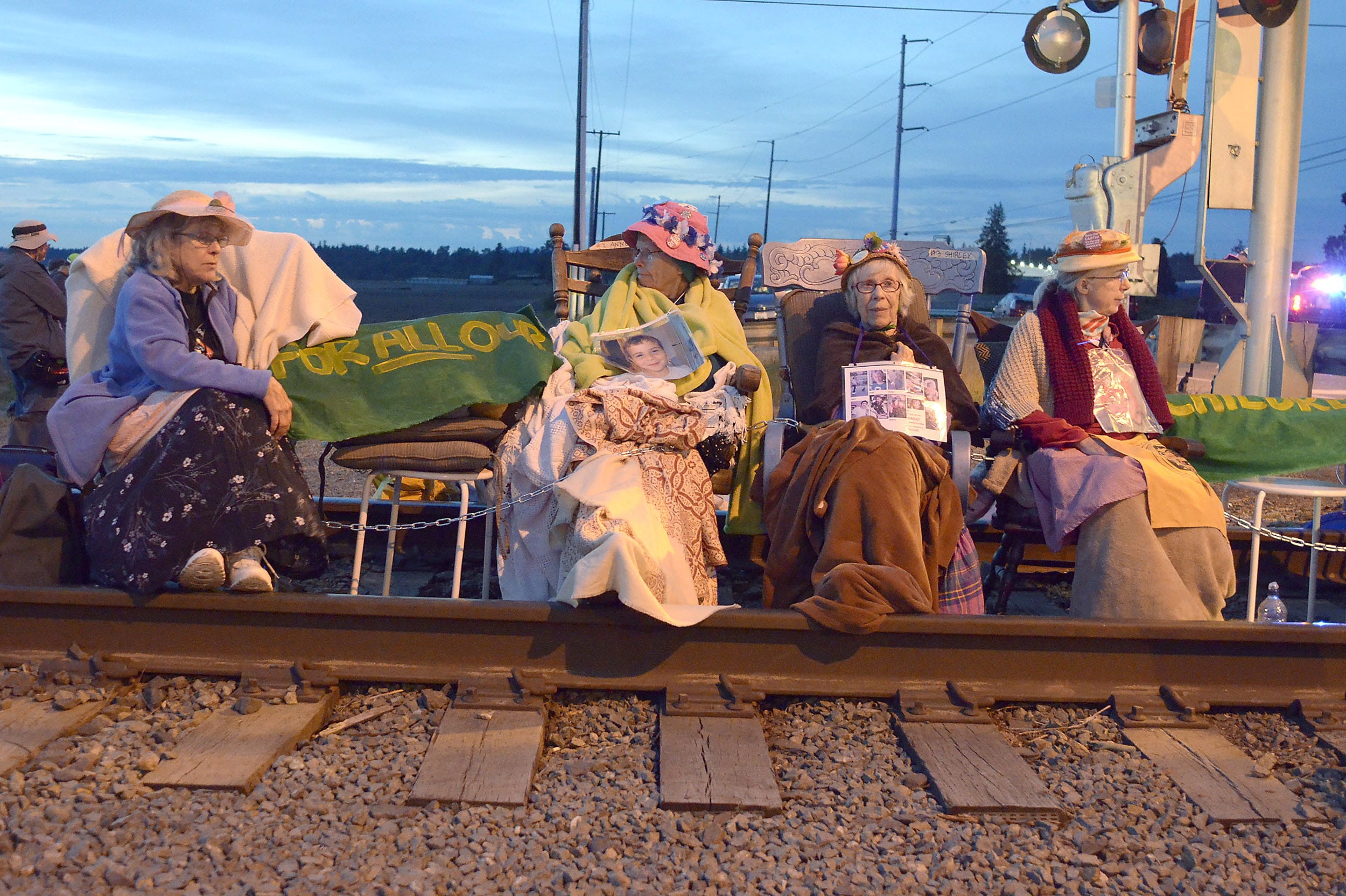 Members of the Seattle Raging Grannies sit in their rocking chairs chained together on the Burlington-Northern Railroad tracks at Farm to Market Road in Skagit County on Friday evening, May 13, 2016, in Burlington, Wash.  From left are Deejay Sherman Peterson, Anne Thureson, Shirley Morrison and Rosy Betz-Zall. Hundreds of people in kayaks and on foot are gathering at the site of two oil refineries in Washington state to call for action on climate change and a fair transition away from fossil fuels.