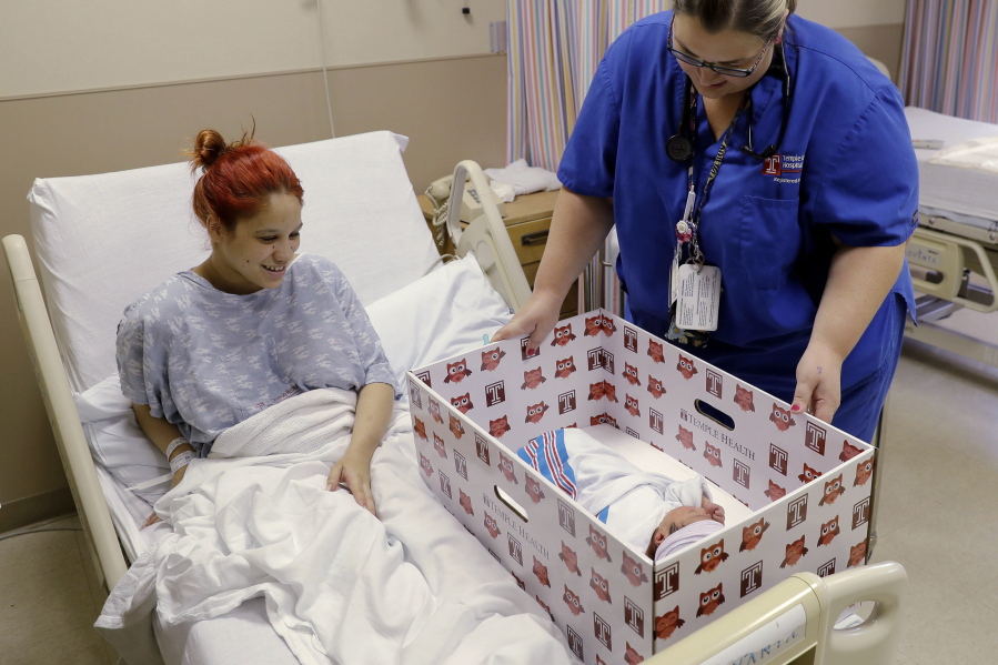 Keyshla Rivera smiles at her newborn son, Jesus, as registered nurse Christine Weick demonstrates a baby box before her discharge from Temple University Hospital in Philadelphia on Friday. In an effort to reduce infant mortality the boxes which are functioning bassinets complete with a sheet and mattress as well as essential baby supplies will be given free-of-charge to all mothers who deliver at the hospital.