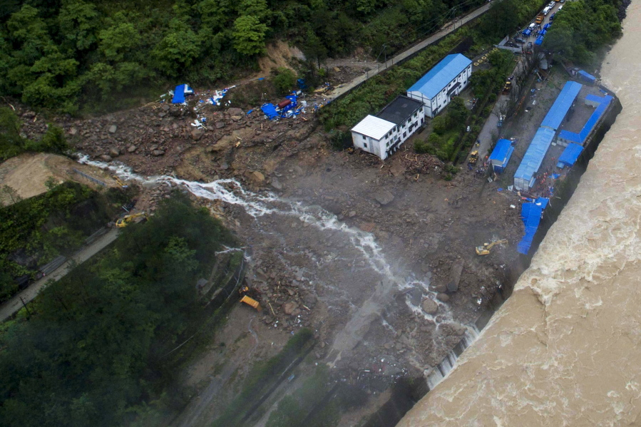 An aerial view shows rescuers search for potential survivors near the building and workers&#039; dormitory damaged by a landslide in Taining county in southeast China&#039;s Fujian province. Several bodies have been found but dozens people were still missing Monday following a landslide at the site of a hydropower project after days of heavy rain in southern China, authorities said.