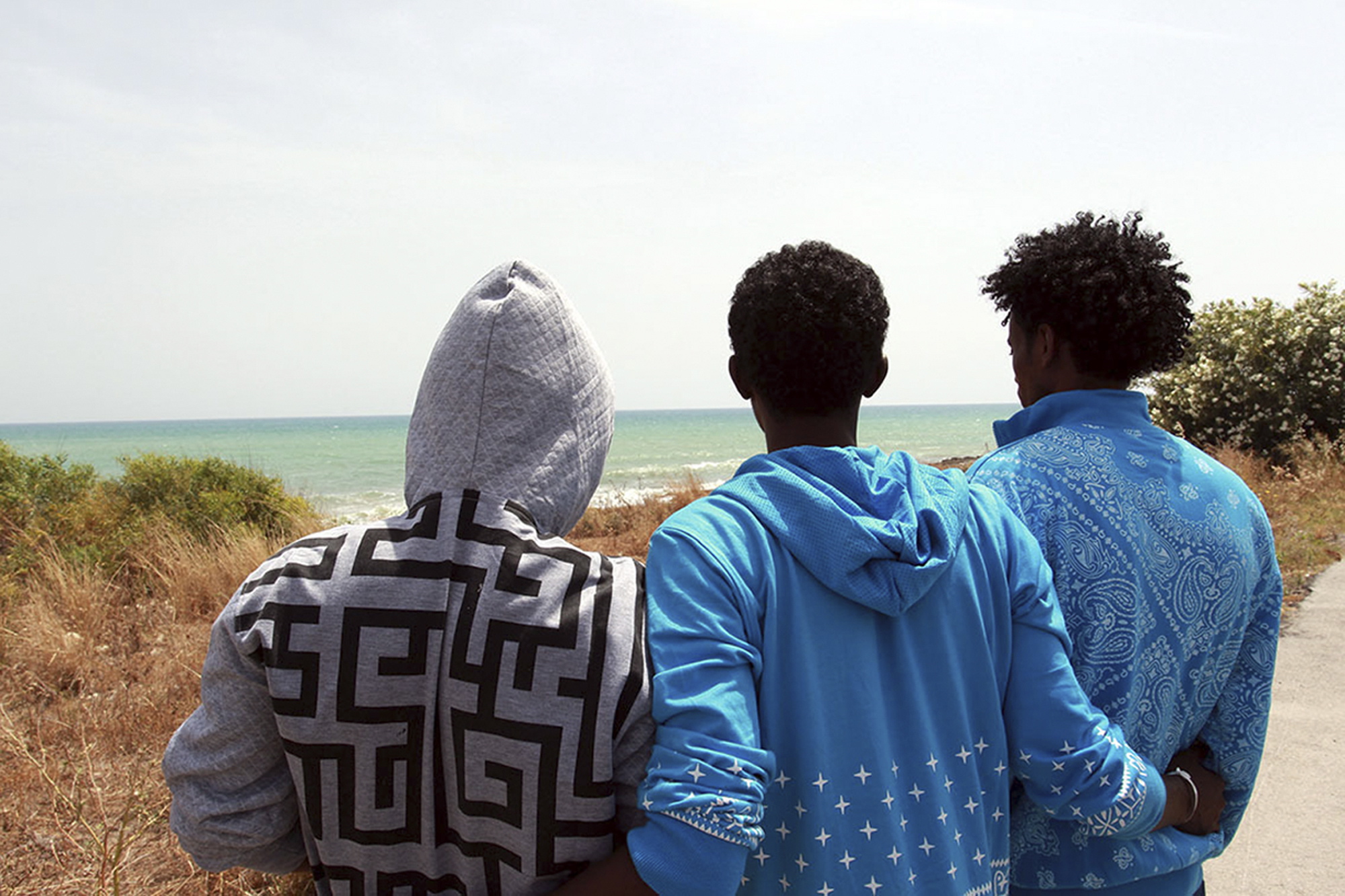 Filmon Selomon, right, Mabtom Tekle, center, and Awad Weldemariam look at the sea during an interview with the Associated Press, in Pozzallo, Sicily, Italy, Sunday, May 29, 2016. They are three Eritrean survivors of an accident that might have produced the largest number of missing and presumed dead, when a wooden fishing boat being towed by another smugglers boat from the Libyan port of Sabratha, sank Thursday. Estimates by police and humanitarian organizations range from around 400 to about 550 missing in that sinking alone.