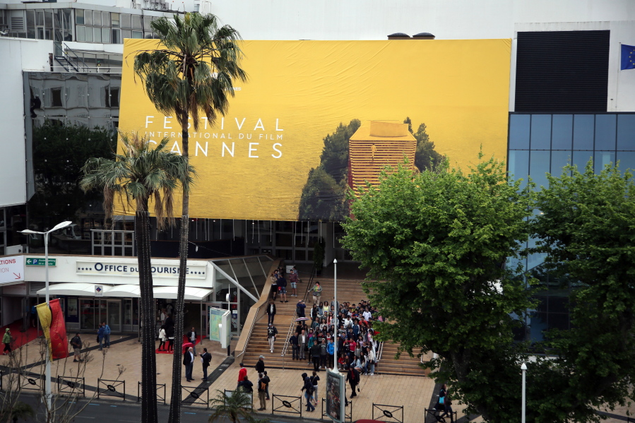 People are photographed Monday in front the official banner on the Palais des Festival during preparations for the 68th international film festival in Cannes, France. The festival runs from today to May 22.